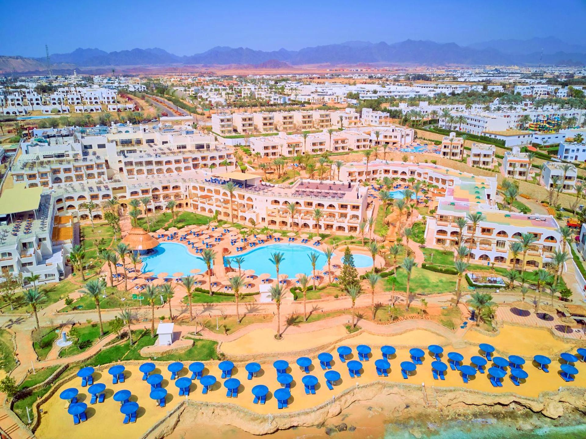 Pickalbatros Royal Grand Sharm - Adults Friendly 16 Years Plus Luaran gambar The photo shows a large resort complex set in a scenic location, likely near a beach. The layout features multiple buildings with a Mediterranean style of architecture, surrounded by lush greenery and palm trees. Central to the resort is a swimming p